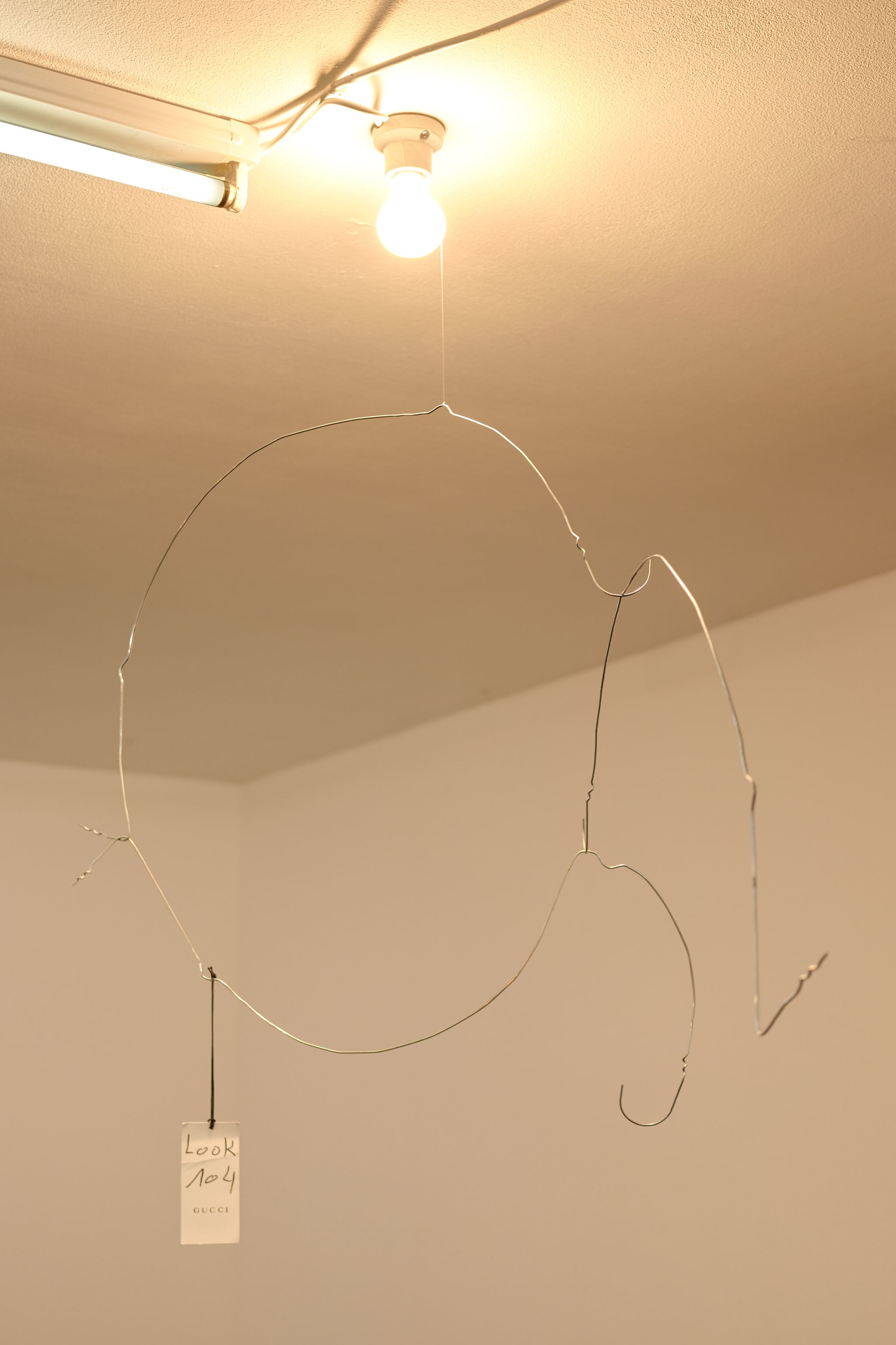 Davide Stucchi, Milan (Mobile 1) Entrance, 2020, Ceramic lamp holder, light bulb, aluminum clothes hangers, tag, 105 ⁠× ⁠100 ⁠× ⁠50 ⁠⁠cm