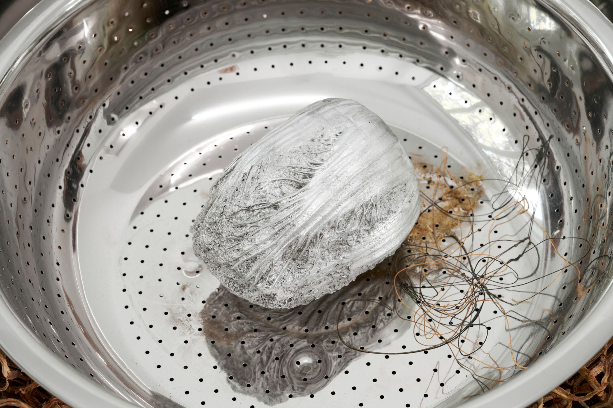 Lotus L. Kang, Mother (Spore, Jan-Mar 2023), 2023, Stainless steel mixing bowls, pigmented silicone, rubber, cast aluminum anchovies, cast aluminum lotus root, cast aluminum kelp knots, cast aluminum dried pear, cast aluminum cabbage, dried carrot, fishing line, hat, Dimensions variable